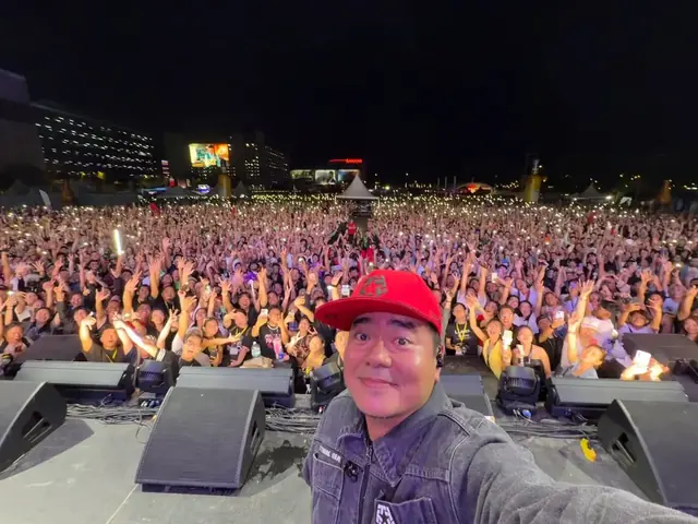 An artist taking a selfie on stage with a huge Howlers crowd with hands in the air behind