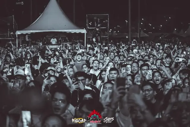 Black and white photo of a happy crowd cheering and filming the stage
