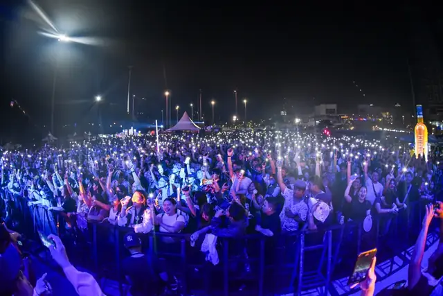 Fans with their hands up under blue stage lights