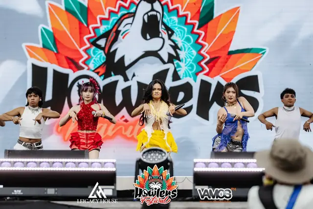 Performers dancing in front of the giant Howlers wolf logo