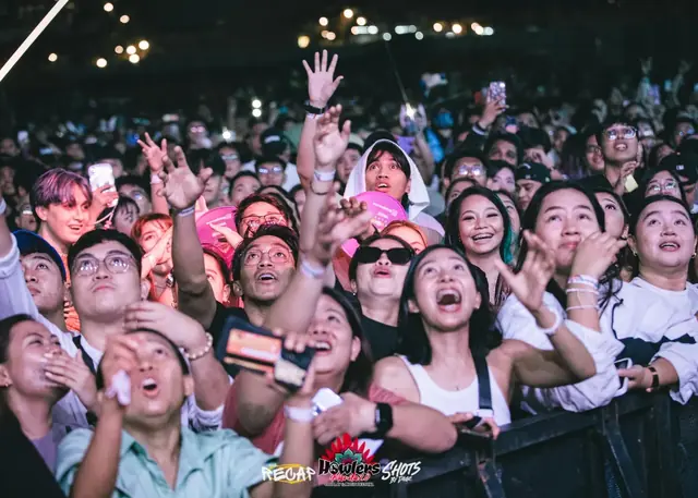 Fans looking up at the stage, smiling and cheering