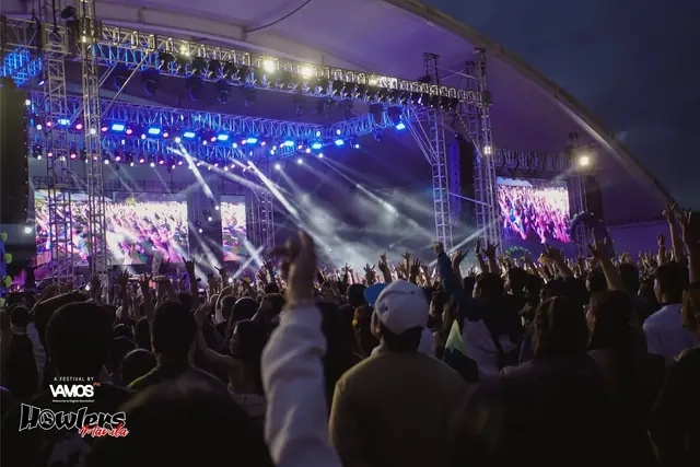 The main stage in purple and blue light with fans' hands in the air